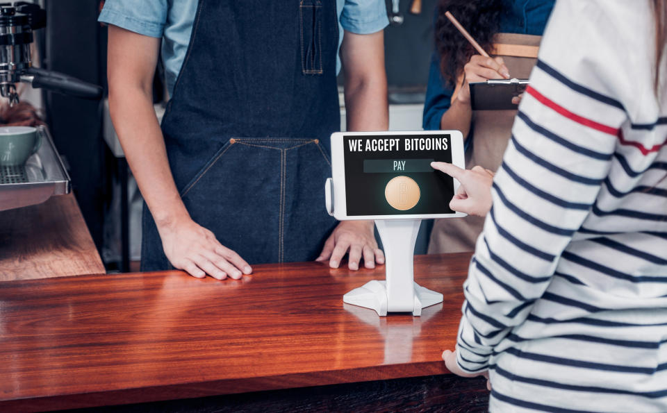 A customer paying with bitcoin on a point-of-sale device in a retail store.