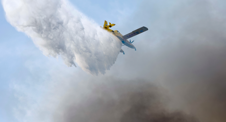 A plane drops water over a bushfire in Spain.