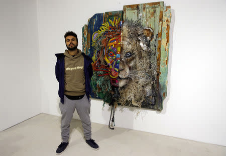 Street artist Bordalo II poses next to one of his creation "Half Lion" (2018) prior to the opening of his exhibition in Paris, France, January 22, 2019. Picture taken January 22, 2019. REUTERS/Philippe Wojazer