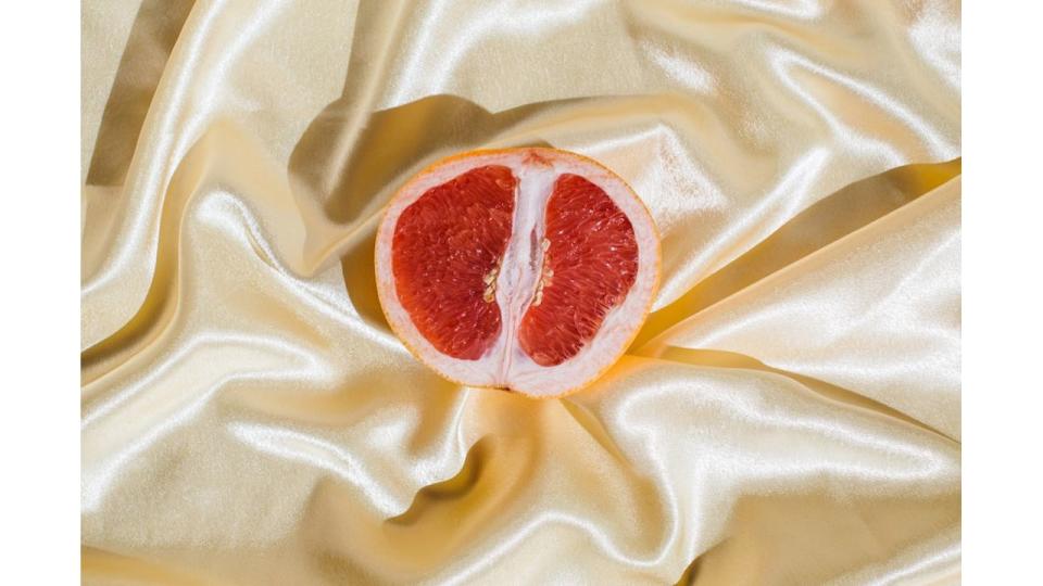 Fresh grapefruit on beige soft silk fabric background