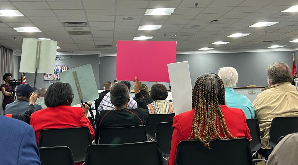 Attendees at the JMCSS Central Office board room hold up signs at the Tennessee Public Charter Commission's appeal hearing for American Classical Academy on September 18, 2023 in Jackson, TN.