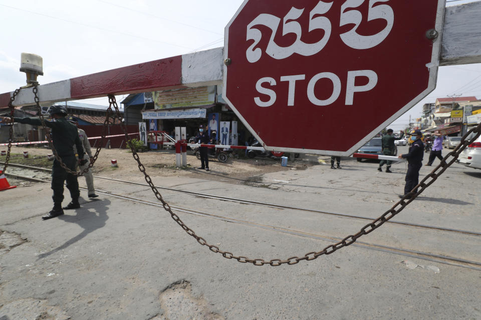 Local police officers stand guard at a blocked street near Phnom Penh International airport in Phnom Penh, Cambodia, Thursday, April 15, 2021. Cambodia’s leader said that the country’s capital Phnom Penh will be locked down for two weeks from Thursday following a sharp rise in COVID-19 cases. (AP Photo/Heng Sinith)