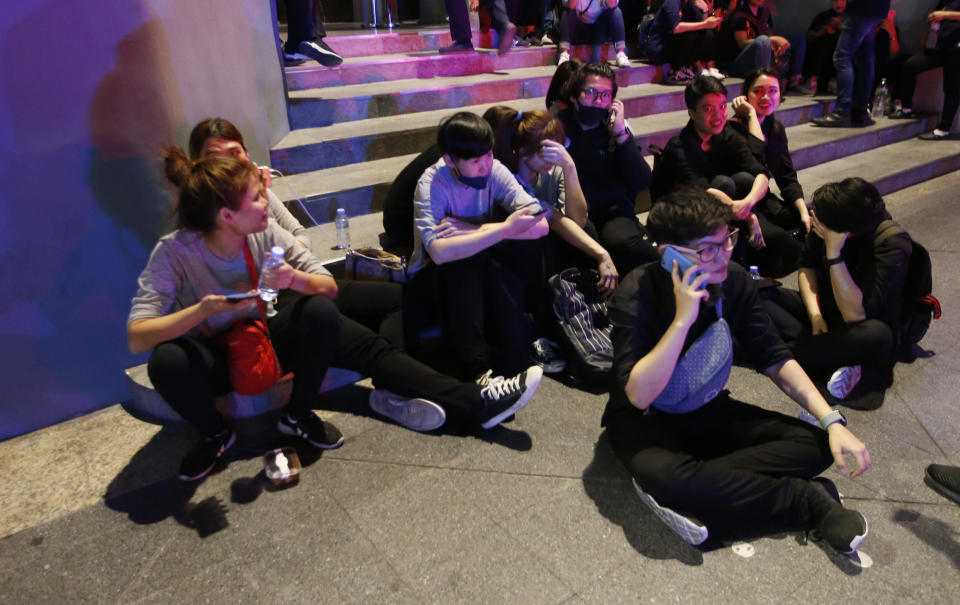 Visitors gather outside after being evacuated from a fire in the Central World mall in Bangkok, Thailand, Wednesday, April 10, 2019. The fire had broken out in the Central World mall complex in Thailand's capital, with reports from emergency services saying it has caused a number of fatalities. (AP Photo/Sakchai Lalit)