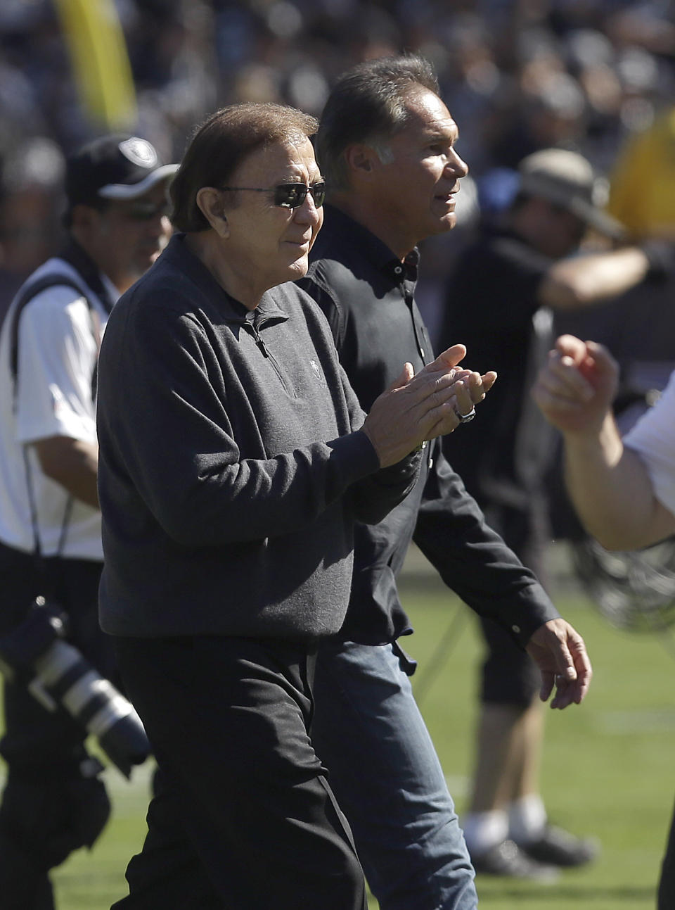 Former Oakland Raiders head coach Tom Flores, left, and former quarterback Jim Plunkett walk off the field after the coin toss as part of Hispanic Heritage Month before an NFL football game between the Raiders and the Arizona Cardinals in Oakland, Calif., Sunday, Oct. 19, 2014. (AP Photo/Jeff Chiu)