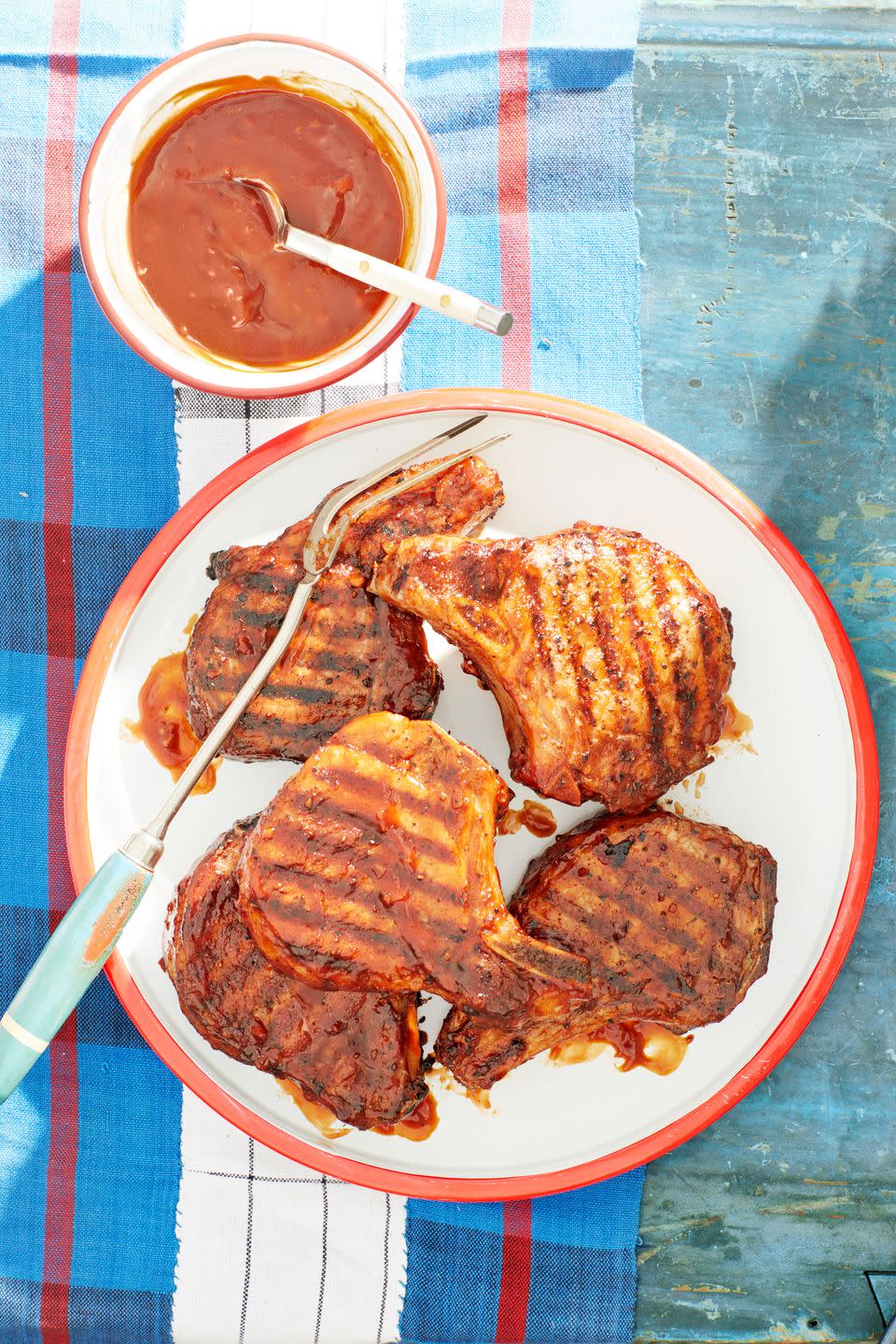 bourbon bbq glazed pork chops arranged on a white plate with red trim