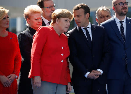 German Chancellor Angela Merkel (C) talks to French President Emmanuel Macron as they gather with NATO member leaders to pose for a family picture before the start of their summit in Brussels, Belgium, May 25, 2017. REUTERS/Jonathan Ernst