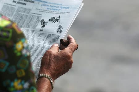 A man smokes a cigar as he reads a local newspaper in Havana, Cuba, September 13, 2016. REUTERS/Alexandre Meneghini