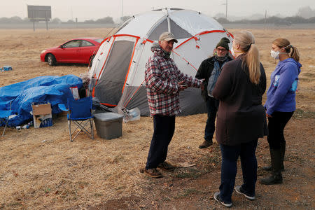 Randy Greb, who lost his house in Paradise in the Camp Fire, talks with employees of the Butte County Department of Employment and Social Services near his tent in a makeshift evacuation center in Chico, California, U.S., November 16, 2018. REUTERS/Terray Sylvester