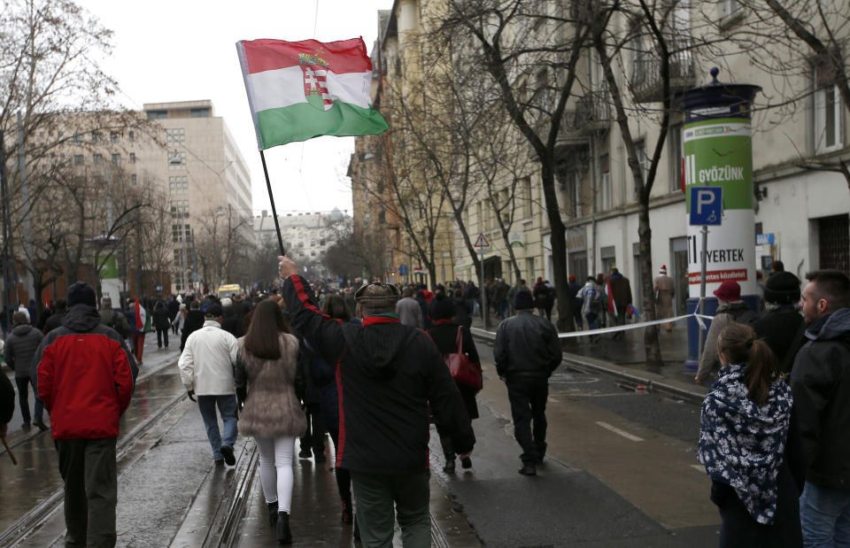 In this March 15, 2018 photo, a supporter of Hungarian Prime Minister Viktor Orban holds a flag outside the Hungarian Parliament building in Budapest, Hungary, during celebrations of the Hungarian national holiday, the 170th anniversary of the outbreak of the 1848 revolution and war of independence against the Habsburgs. With a campaign centered on stopping immigration, Hungary’s ruling Fidesz party is expected to continue its dominance in the European Parliament election at the end of May. While Hungary has been practically closed to immigrants from the Middle East, Asia and Africa since Prime Minister Viktor Orban had border fences built in 2015, he continues to warn voters about the threat of a “migrant invasion” that would put at risk Europe’s Christian culture. (AP Photo/Darko Vojinovic)