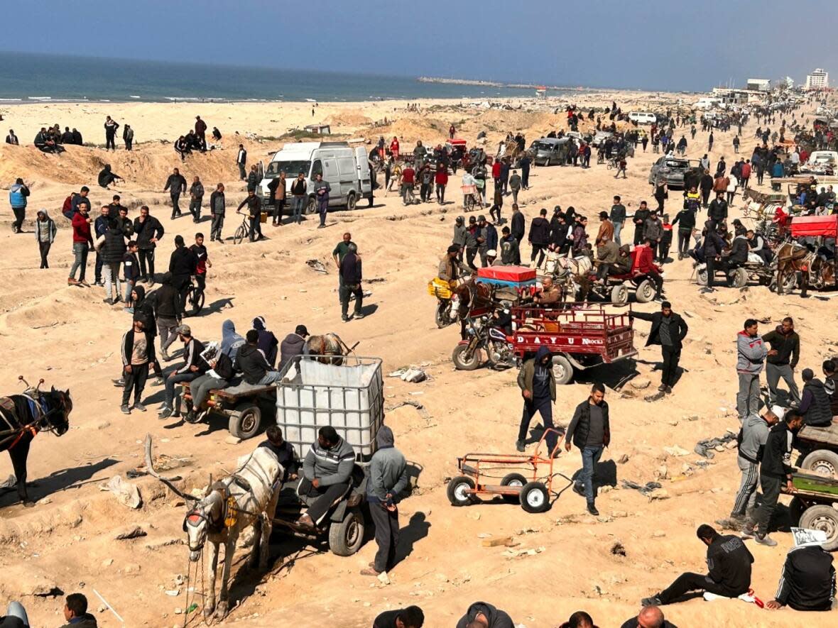 Palestinians wait for humanitarian aid on a beachfront in Gaza City on Sunday, Feb. 25, 2024. (Mahmoud Essa/The Associated Press - image credit)