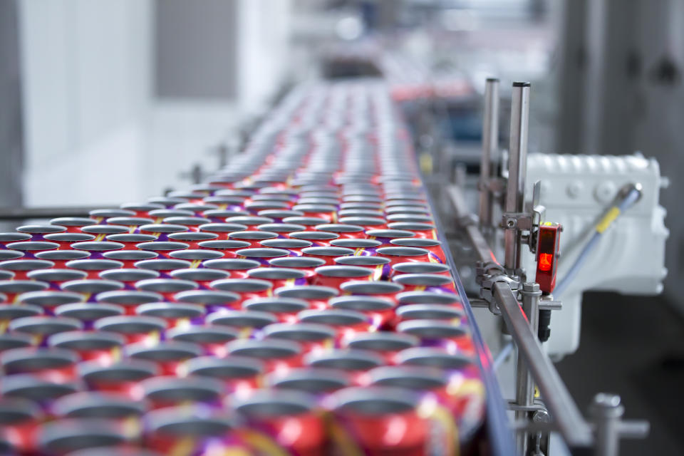 Filling of colorful beverage cans on production line.