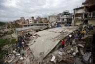 People gather near a collapsed house after a major earthquake in Kathmandu, Nepal April 25, 2015. A shallow earthquake measuring 7.9 magnitude struck west of the ancient Nepali capital of Kathmandu on Saturday, killing more than 100 people, injuring hundreds and leaving a pall over the valley, doctors and witnesses said. REUTERS/Navesh Chitrakar TPX IMAGES OF THE DAY