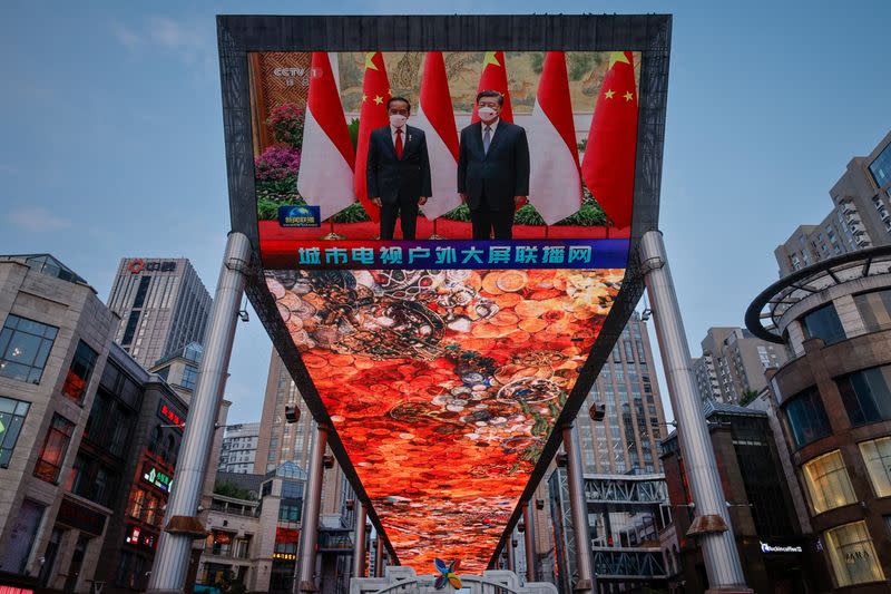 A screen shows a CCTV state media broadcast of Chinese President Xi Jinping meeting Indonesian President Joko Widodo at a shopping mall in Beijing