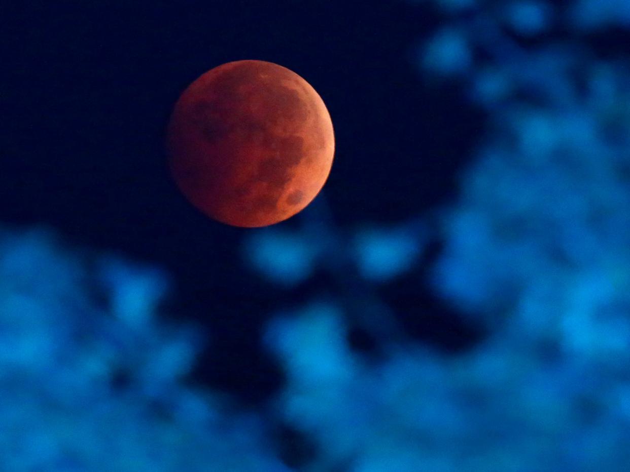 A total lunar eclipse is seen over Milwaukee on Oct. 7, 2014. The moon appears orange or red, the result of sunlight scattering off Earth's atmosphere. This is known as the blood moon. A total 'super flower blood moon' lunar eclipse will be visible across Wisconsin on Sunday night.