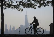 A woman rides her bicycle past the skyline of New York's Lower Manhattan and One World Trade Center in a park along the Hudson River in Hoboken, New Jersey, September 11, 2013. Americans marked the 12th anniversary of the 9/11 attacks with solemn ceremonies and pledges not to forget the nearly 3,000 killed when hijacked jetliners crashed into the World Trade Center, the Pentagon and a Pennsylvania field, in 2001. (REUTERS/Gary Hershorn)