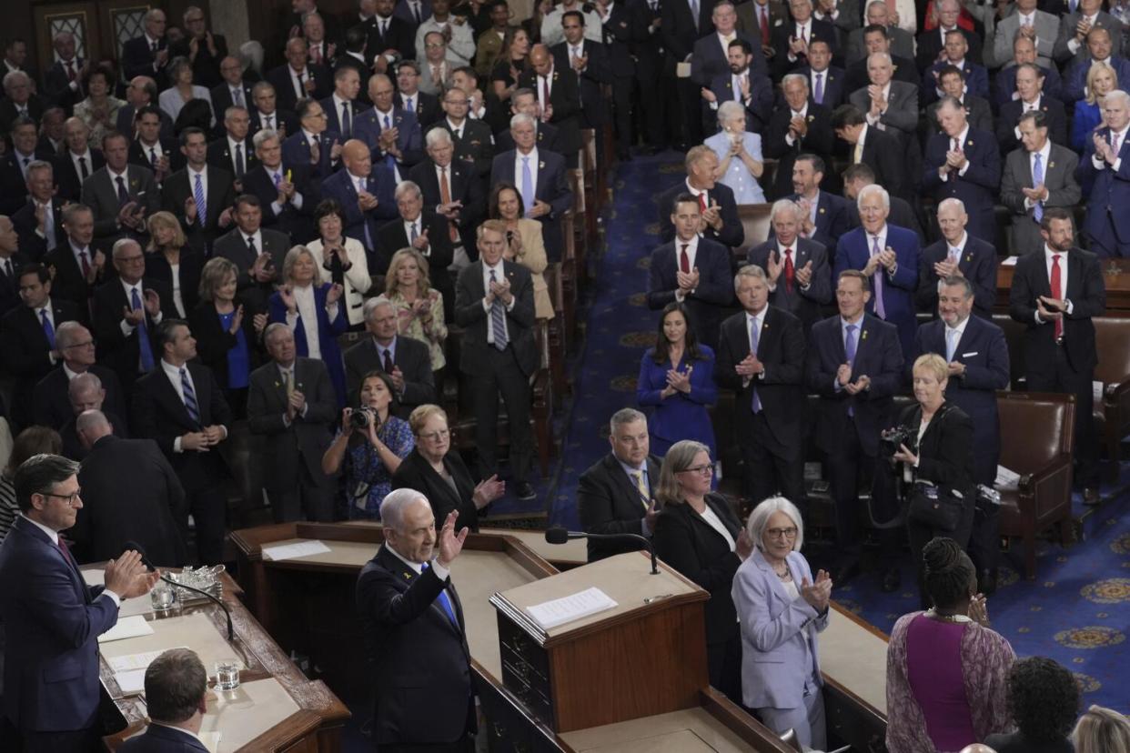 Benjamin Netanyahu waves as lawmakers stand and applaud