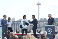 Brandon Tanev, center, a forward from the Pittsburgh Penguins, is introduced as a player for the Seattle Kraken, Wednesday, July 21, 2021, during the Kraken's NHL hockey expansion draft event in Seattle. Looking on are ESPN hosts Dominic Moore, left, and Chris Fowler, second from right, and Kraken general manager Ron Francis, right, and Kraken scout Cammi Granato, second from left. (AP Photo/Ted S. Warren)