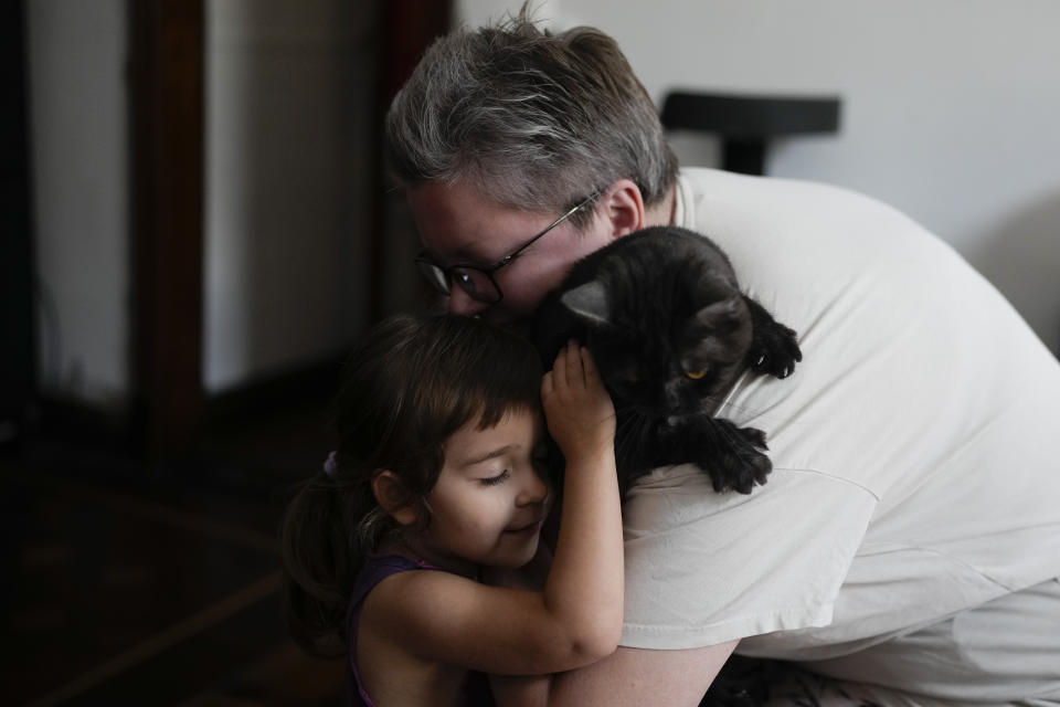 Anna Domini and her 3-year-old daughter Agata, embrace their pet cat Faust, at their home in Buenos Aires, Argentina, Saturday, April 22, 2023. Anna, who married her same-sex partner Anatasia shortly after arriving in Buenos Aires, is part of a growing number of LGBTQ+ Russians seeking refuge from war and discrimination in Argentina. (AP Photo/Natacha Pisarenko)