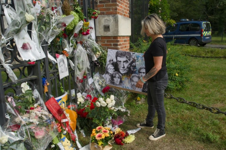 Una mujer observa las flores y retratos en recuerdo de Alain Delon depositados a la entrada de la casa del fallecido actor en Douchy, el 20 de agosto de 2024 en el centro de Francia (Guillaume Souvant)