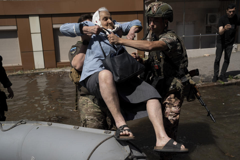 A woman is evacuated from a flooded neighborhood in Kherson, Ukraine, Wednesday, June 7, 2023 after the walls of the Kakhovka dam collapsed. Residents of southern Ukraine braced for a second day of swelling floodwaters on Wednesday as authorities warned that a Dnieper River dam breach would continue to unleash pent-up waters from a giant reservoir. (AP Photo/Roman Hrytsyna)