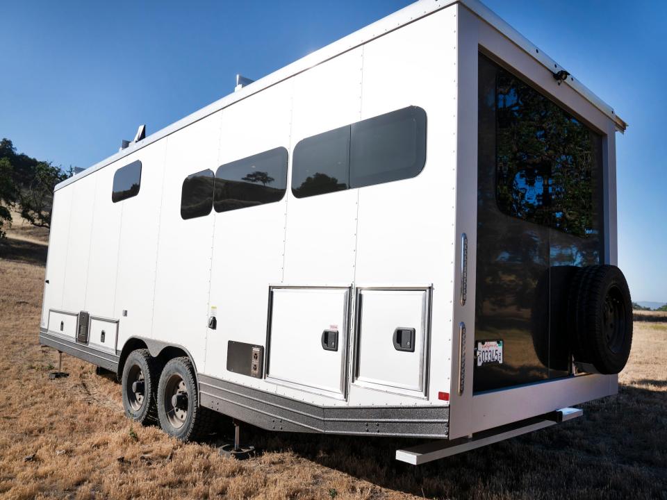 The a close up of the exterior of the travel trailer as it sits on a brown field.