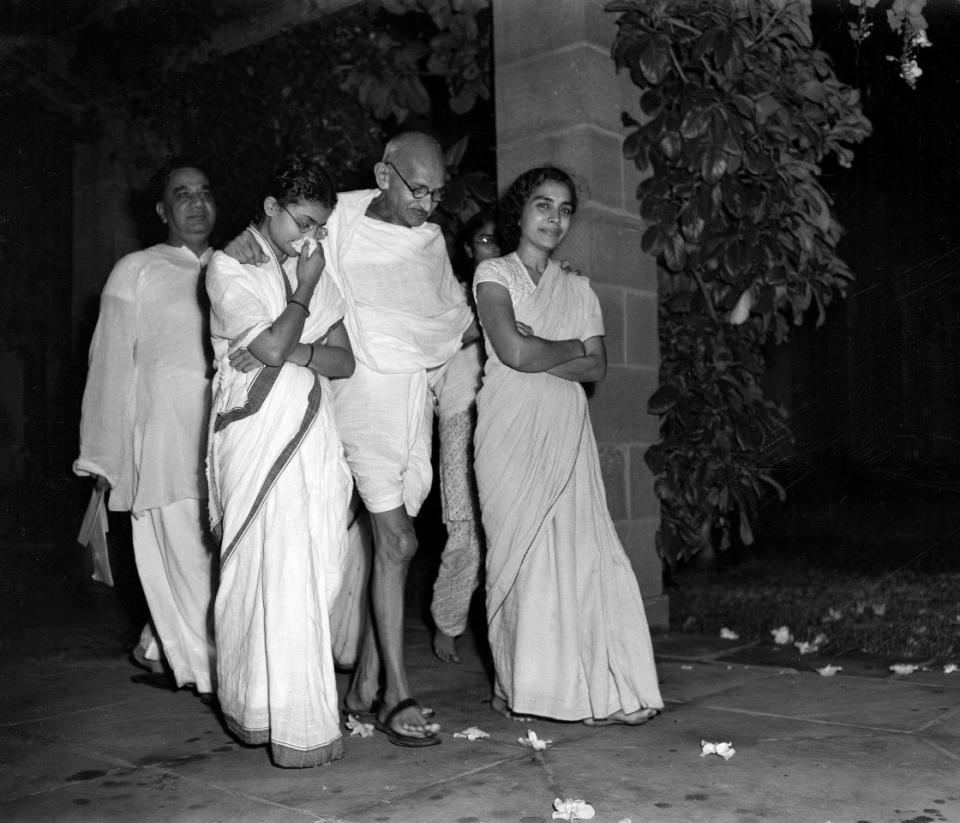 GANDHI BIRTHDAY: Mahatma Gandhi, center, accompanied by Abha Gandhi, left, and Dr. Sushila Nayyar, right, one of his attendants during his present illness, is shown walking in the garden of Birla House, New Delhi, India, October 2, 1947, as he celebrates his 78th birthday. H.S. Suhrawardy, former chief minister of Bengal Province, is at extreme left, rear. (AP Photo)