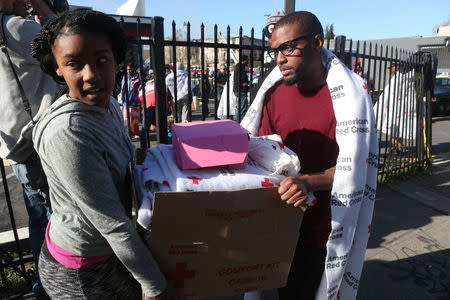 Justin Wash (R) and his sister Eliza Anderson carry a box with their only possessions after a four-alarm blaze destroyed their apartment #315 in a three-story building in Oakland, California, U.S. March 27, 2017. REUTERS/Beck Diefenbach