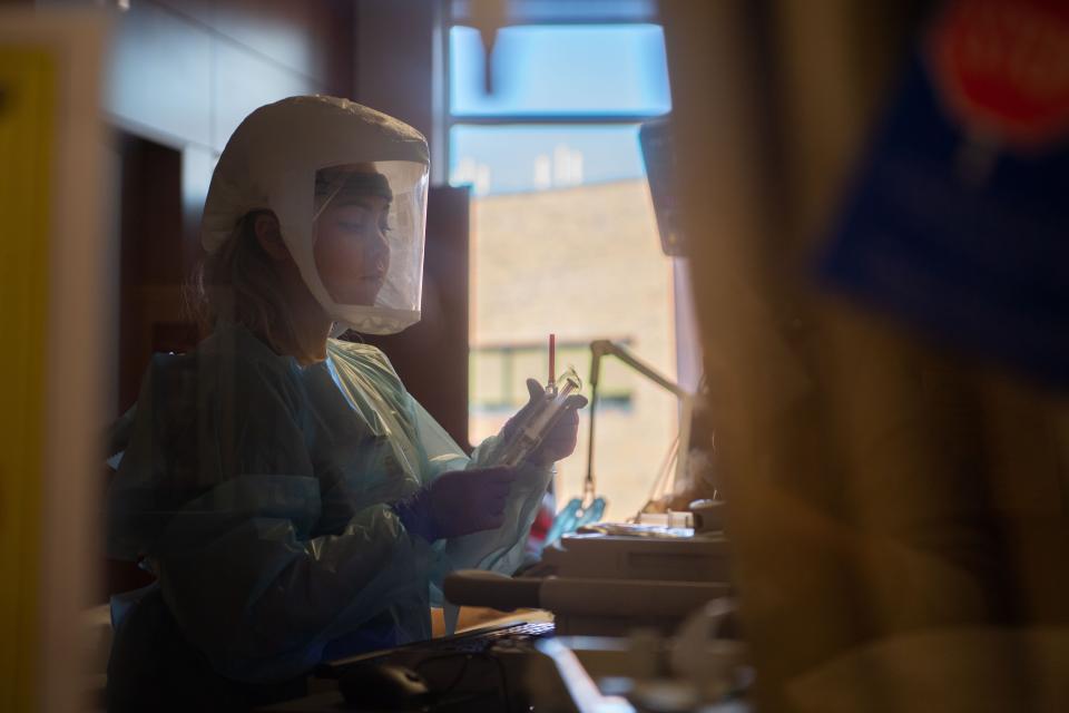 Nurse Molly Bernard cares for a COVID-19 patient in the room with protective gear on at Vanderbilt ICU  in Nashville, Tenn., Monday, Jan. 10, 2022.