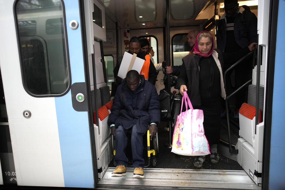 ARCHIVO - Babou Sene, a la izquierda, recibe ayuda al salir de un tren en la Gare de Lyon, el miércoles 26 de abril de 2023, en París. (AP Foto/Christophe Ena)