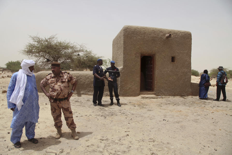 FILE - People attending a ceremony stand near a mausoleum, right, that was restored in Timbuktu, Mali, July 18, 2015, after the 14 mausoleums in Mali's northern historic city that had been destroyed by Islamic extremists in 2012 have been restored. The International Criminal Court unsealed an arrest warrant Friday June 21, 2024, for a Malian accused of war crimes and crimes against humanity in the desert city of Timbuktu in 2012-13, where he is suspected of leading an al-Qaida-linked Islamic extremist group. (AP Photo/Baba Ahmed, File)