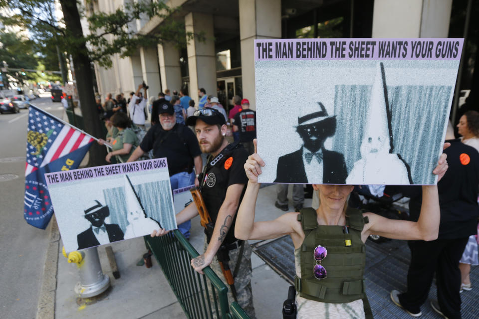 Gypsy Gonzalez, right, and Adam Root, of Richmond, hold weapons as well as a photo that was in Gov. Ralph Northam's yearbook outside an office building at the State Capitol in Richmond, Va., Tuesday, July 9, 2019. Governor Northam called a special session of the General Assembly to consider gun legislation in light of the Virginia Beach Shootings. (AP Photo/Steve Helber)