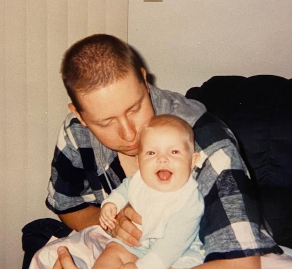 A baby Caitlin sits happily on the lap of her father, Curtis, who died when she was three and a half years old (Darlene Jensen)