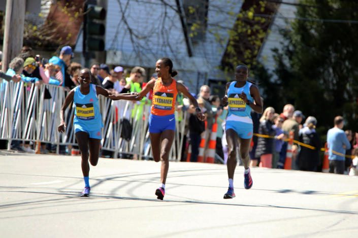 Peres Jepchirchir, of Kenya, left, and Ababel Yeshaneh, of Ethiopia, clasp each others arms during the 126th Boston Marathon in Newton, Mass., Monday, April 18, 2022. Jepchirchir won the women's division and Yeshaneh finished second. At right is Joyciline Jeopkosgei, of Kenya. (AP Photo/Jennifer McDermott)