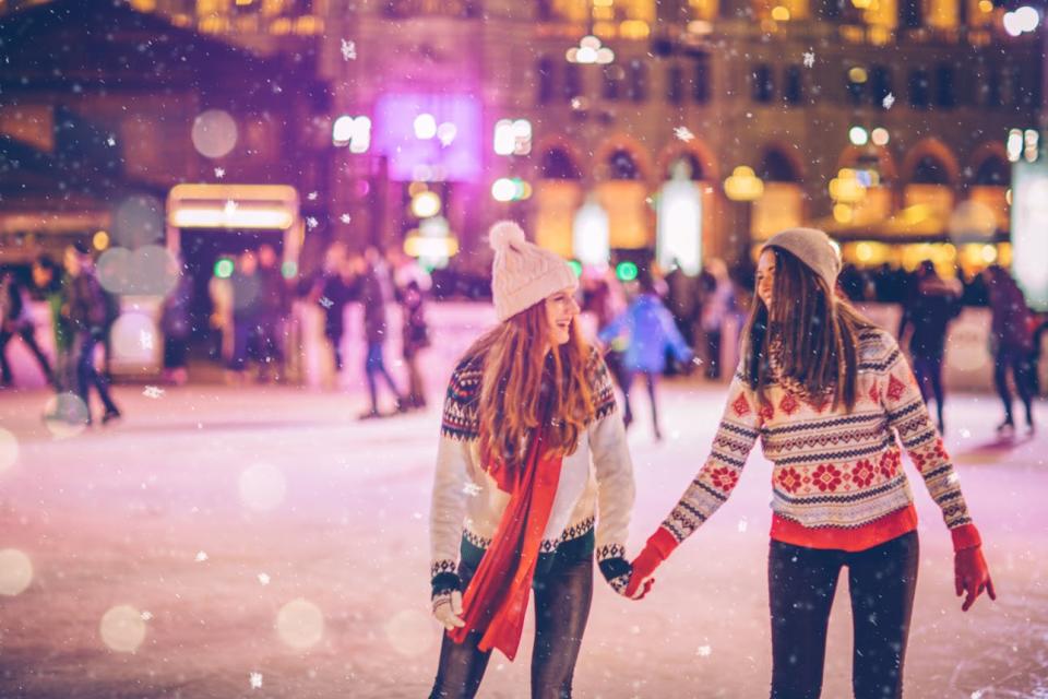 Friends ice skate hand in hand