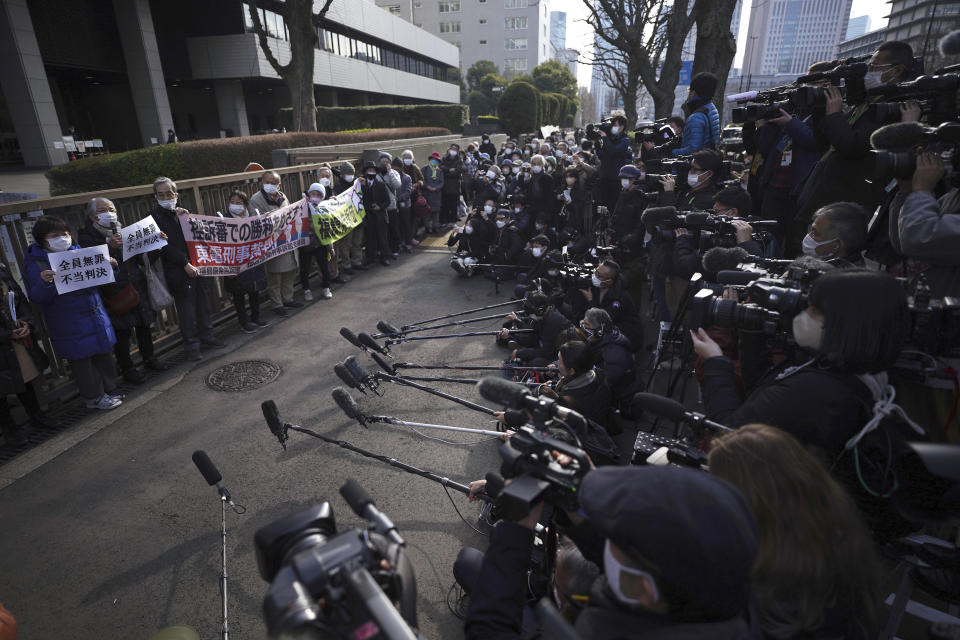 Yoshiko Furukawa, far left, and Etsuko Kudo, second left, supporters of the plaintiff hold a cloth sign that reads "All not guilty, Unfair judgment," outside of the Tokyo High Court in Tokyo Wednesday, Jan. 18, 2023. The court on Wednesday found three former executives of Tokyo Electric Power Company not guilty of negligence over the 2011 Fukushima nuclear meltdowns and subsequent deaths of more than 40 elderly residents during their forced evacuation. (AP Photo/Eugene Hoshiko)