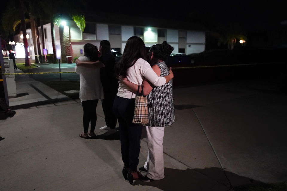 Unidentified people comfort each other as they stand near a business building where a shooting occurred in Orange, Calif., Wednesday, March 31, 2021. Police say several people were killed, including a child, and the suspected shooter was wounded by police. (AP Photo/Jae C. Hong)