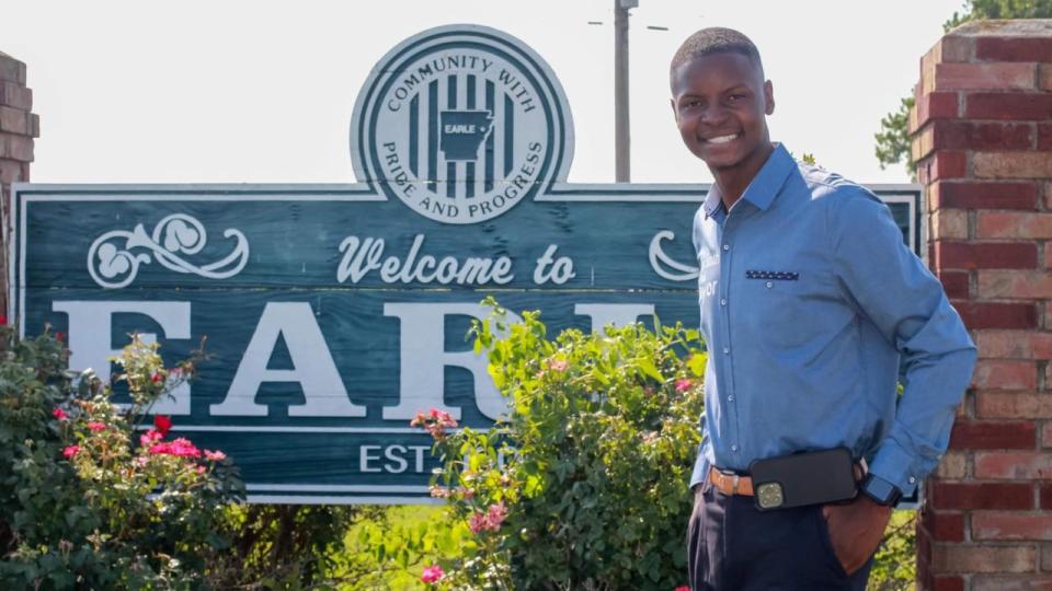 Jaylen Smith stands in front of a town sign that reads, 