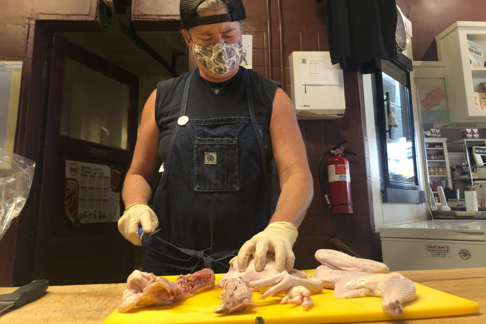 Owner Angela Wilson breaks down a whole chicken at Avedano's Meats in San Francisco, Wednesday, Oct. 21, 2020. Due to the ongoing coronavirus pandemic and restrictions on large gatherings, the traditional Thanksgiving feast is being downsized. Fewer people at Thanksgiving tables means many families will buy smaller turkeys, or none at all. On her Thanksgiving orders, Wilson said "we don't want as many big birds and we think we'll sell smaller birds or different things like porcheta or guinea fowl, quails, fresh game hen." (AP Photo/Haven Daley)