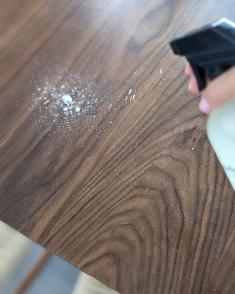 Someone spraying Everneat cleaner on dining table.