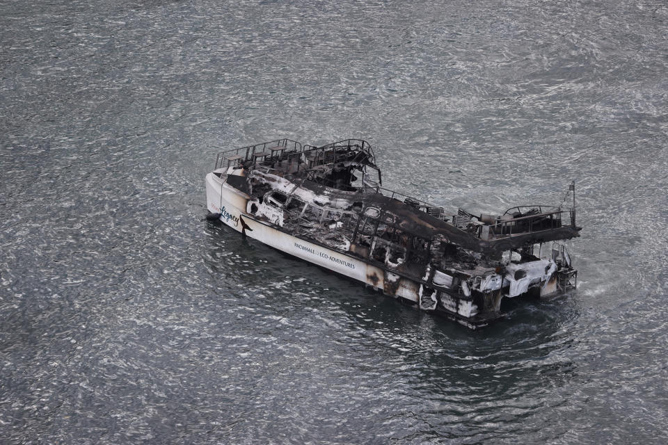 A blackened boat floating in the ocean off Lahaina.