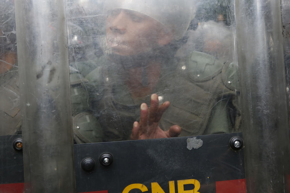 A National Guard soldier pushes his shield against members of the press and opposition lawmakers inside the grounds of the National Assembly in Caracas, Venezuela, Tuesday, Jan. 7, 2020. Venezuelan opposition leader Juan Guaidó and lawmakers who back him pushed their way into the legislative building on Tuesday following an attempt by rival legislators to take control of the congress. (AP Photo/Andrea Hernandez Briceño)
