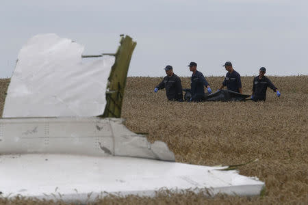 Members of the Ukrainian Emergency Ministry carry a body at the crash site of Malaysia Airlines Flight MH17, near the settlement of Grabovo in the Donetsk region July 19, 2014. REUTERS/Maxim Zmeyev