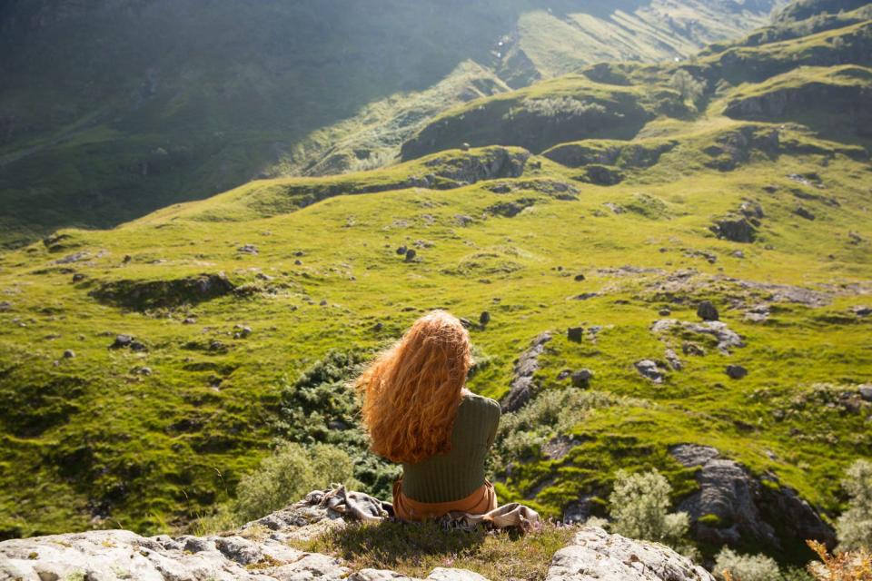 A redheaded woman named Kristie from Glencoe, Scotland, looks out at a landscape