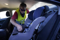 Dave, who declined to give his last name, from Toledo, Ohio, installs a child seat in his vehicle as he waits to for his friend Ruth, a Haitian migrant, her husband and their 3-year-old daughter, who he believes continue to be in U.S. Customs and Border Protection custody, Friday, Sept. 24, 2021, in Del Rio, Texas. Dave, who has been to Haiti many times and befriended Ruth on one of his trips, drove down from Ohio to Southwest Texas in hopes of picking the family up and driving them to Ohio, where Ruth has family awaiting them. (AP Photo/Julio Cortez)