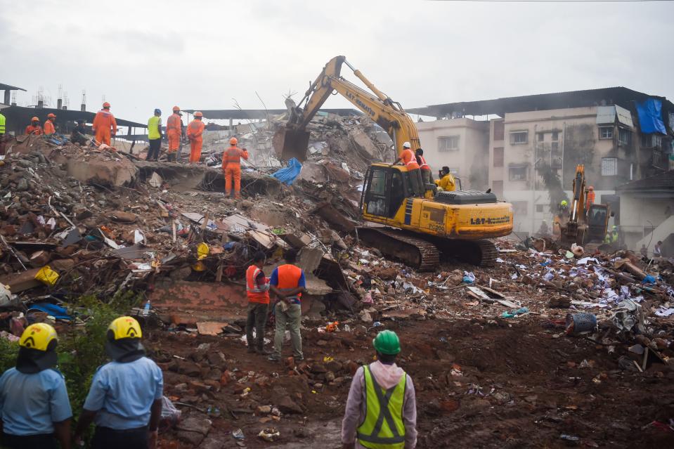 Rescue workers search for people in the rubble of a collapsed five-storey apartment building in Mahad. (Photo by PUNIT PARANJPE/AFP via Getty Images)