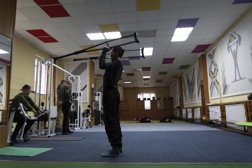 Ivan Moroz, who was injured while working in a gas production facility, exercises alongside Ukrainian soldiers in a physical therapy room at a rehabilitation center in Kharkiv region, Ukraine, Friday, Dec. 30, 2022. (AP Photo/Vasilisa Stepanenko)