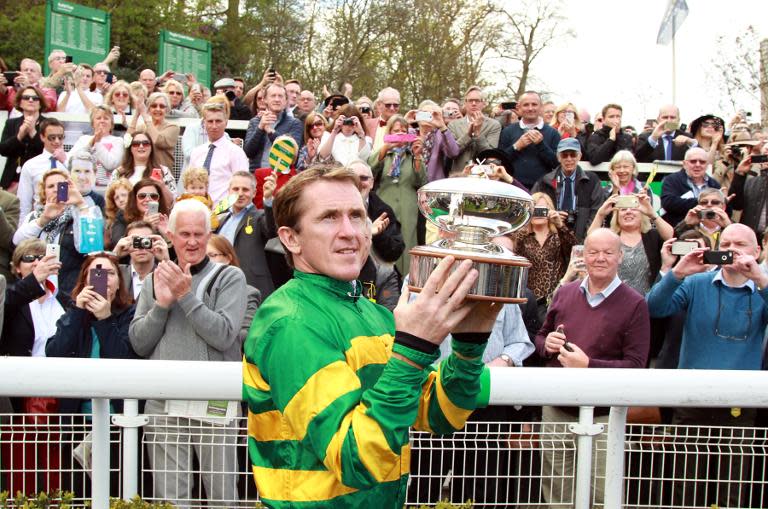 Northern Irish jockey Tony McCoy holds up the jockey championship cup presented to him on his retirement at Sandown Park Racecourse in Esher on April 25, 2015