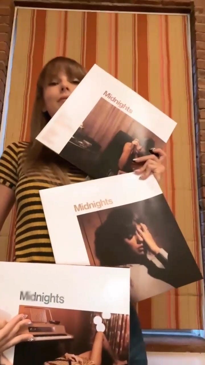 Taylor Swift holding up vinyl copies of her 10th studio album, "Midnights.