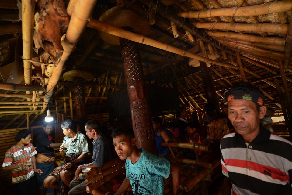 TO GO WITH AFP STORY INDONESIA-CULTURE-TOURISM, FEATURE BY ANGELA DEWAN In this photograph taken on March 22, 2014, Sumbanese tribesmen and women gather inside their traditional home in Ratenggaro village located in Indonesia's island of Sumba, the site for the the annual "pasola" festival, a ritual mock battle on horseback. Two teams of tribesmen on horseback charge at each other hurling bamboo spears in a thousand-year-old ritual on the Indonesian island of Sumba aimed at producing a prosperous rice harvest. Spectators, their mouths reddened from chewing betel nut, scream them on from the sidelines of the show in Ratenggaro village, reaching for their machetes when a rider is struck at close range and the referee calls foul play. AFP PHOTO / ROMEO GACAD        (Photo credit should read ROMEO GACAD/AFP via Getty Images)