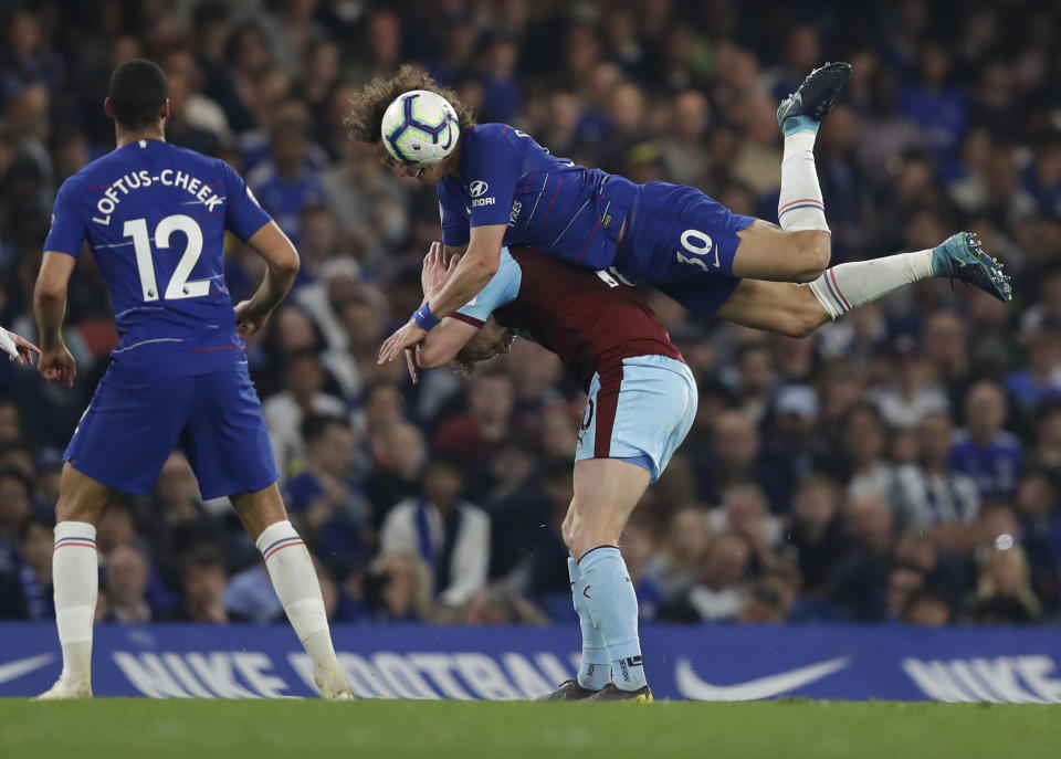 Chelsea's David Luiz flies over Burnley's Ashley Barnes during the English Premier League soccer match between Chelsea and Burnley at Stamford Bridge stadium in London, Monday, April 22, 2019. (AP Photo/Kirsty Wigglesworth)